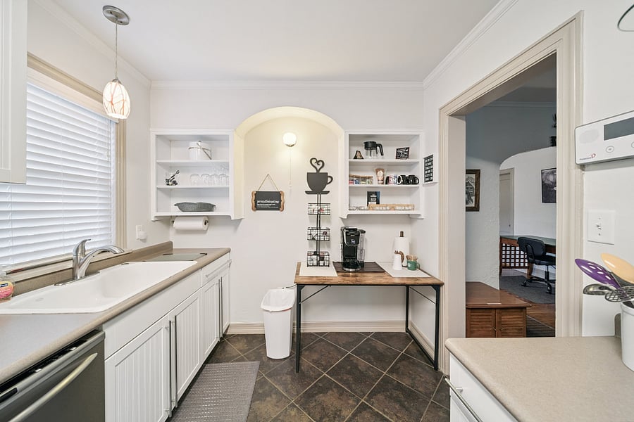 A second view of the coffee bar highlights the charming open shelving, blending the home's historic character with modern convenience. The shelves are stocked with mugs, glassware, and kitchen essentials, while the dedicated coffee station provides everything you need to start your morning with a fresh cup of coffee in a warm and welcoming setting.