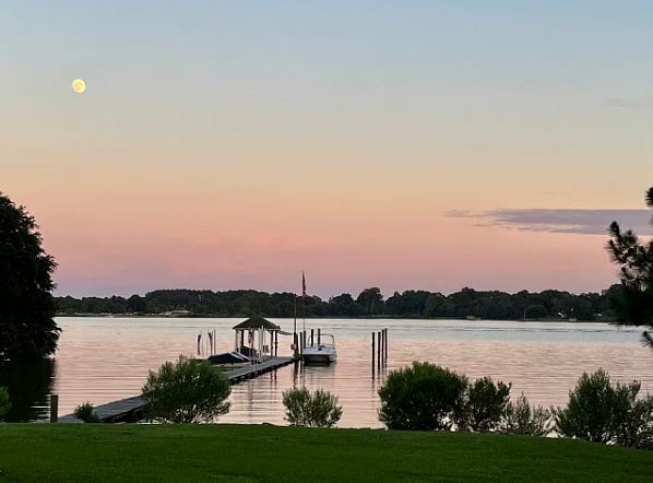 Scenic waterfront view featuring a wooden dock and vibrant sunset reflections on the lake.