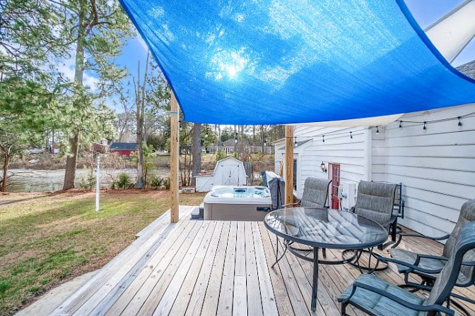 Lakefront outdoor area with hot tub, open lawn, and beautiful water views.