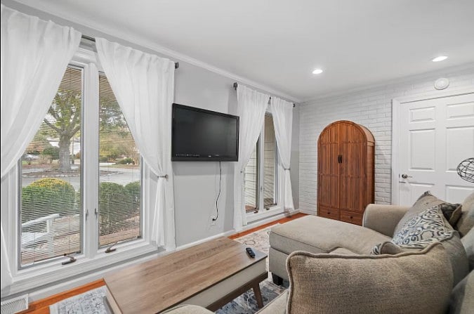 Bright living room with large windows, natural light, and a wall-mounted TV.