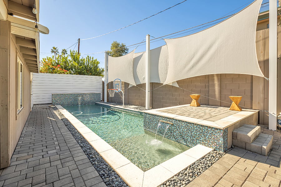 Secluded backyard oasis with custom privacy structures and a sparkling pool with dual waterfalls