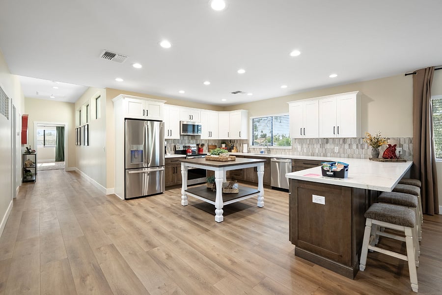 The wide-open floor plan seamlessly connects the kitchen to a bright hallway leading to the rest of the home, creating an inviting, airy atmosphere.