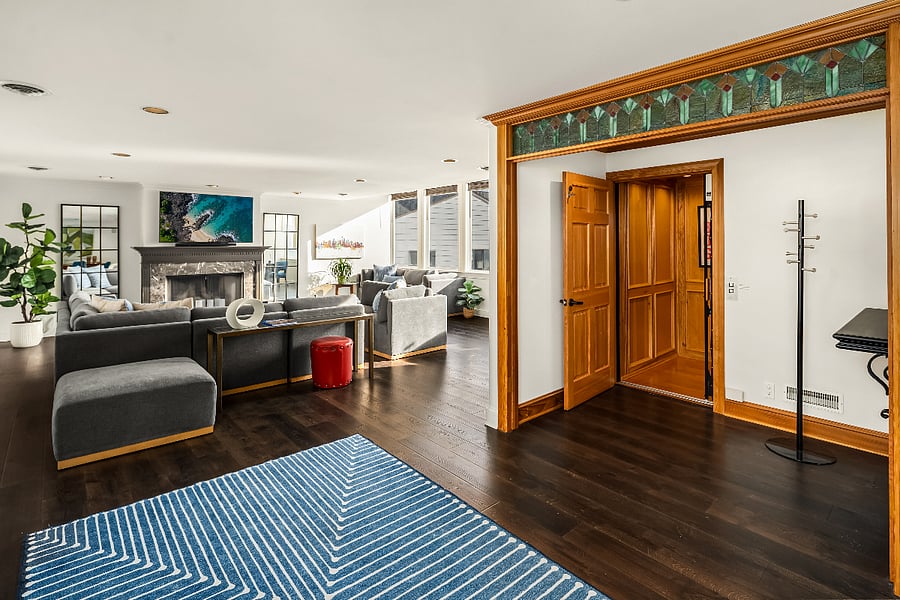 Elevator entry to apartment has a small lobby with coat rack and console for purses and keys. The open floor plan has living room on right and dining kitchen on the left.