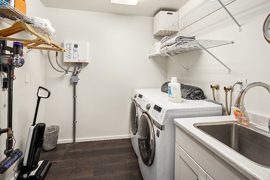 Dedicated in apartment laundry room with washer and dryer, laundry sink and plenty of storage.