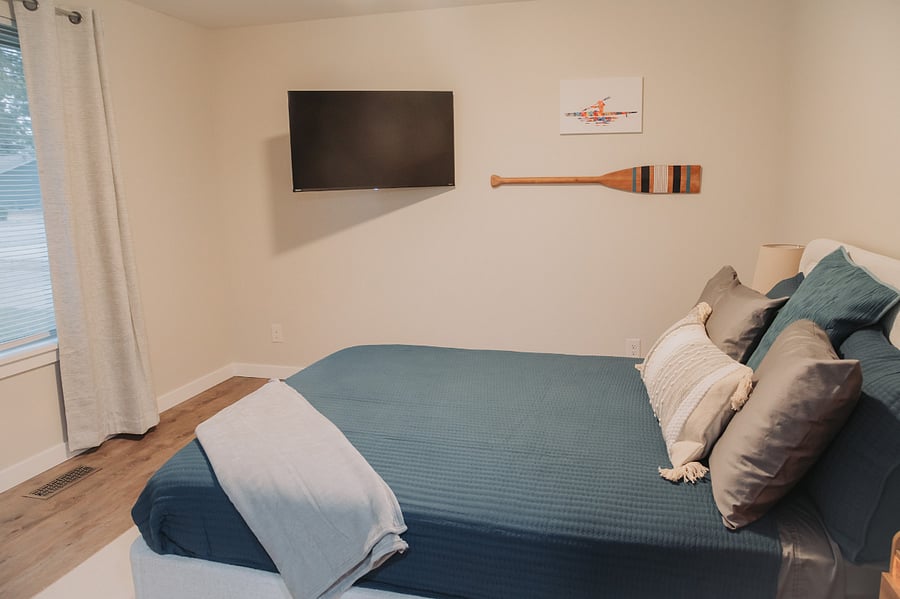 Bedroom Two features a cozy queen bed, lamps, a large closet space and a Roku TV that pulls out from the wall to a comfortable viewing position