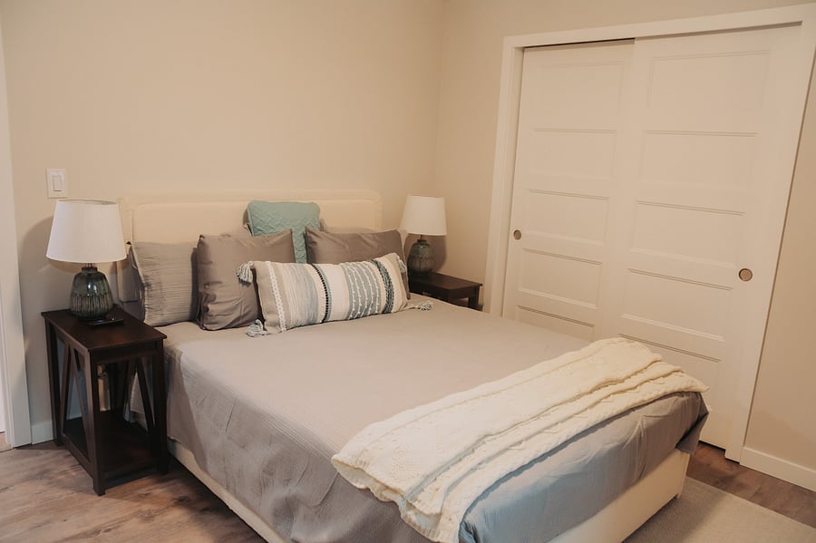 Guest bedroom 1, a luxurious queen bed with lamps, a large picture window and plenty of space. This room features a TV which pulls out from the wall for easy viewing.