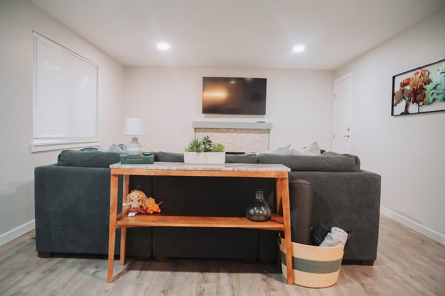 The fireside living room features an electric fireplace, work space with adjustable chair and desk, and a large comfortable couch for the perfect movie night.