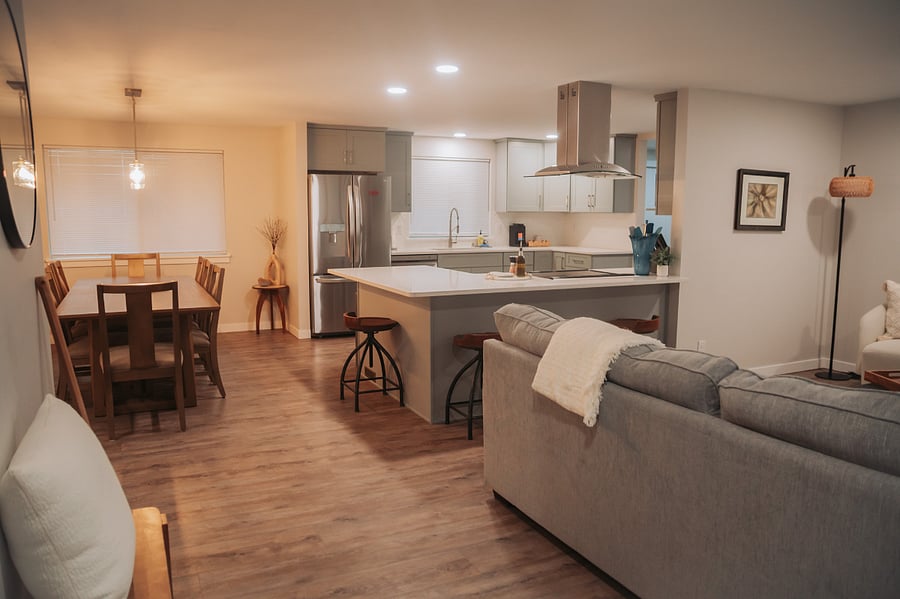 View from the front door: first living room to the right, large eight person dining table straight ahead, open concept kitchen with bar seating for four.