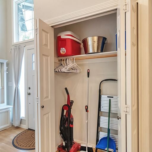 Hall closet contains Swiffer, new vacuum, broom, toys, cooler, step stool, hangers.