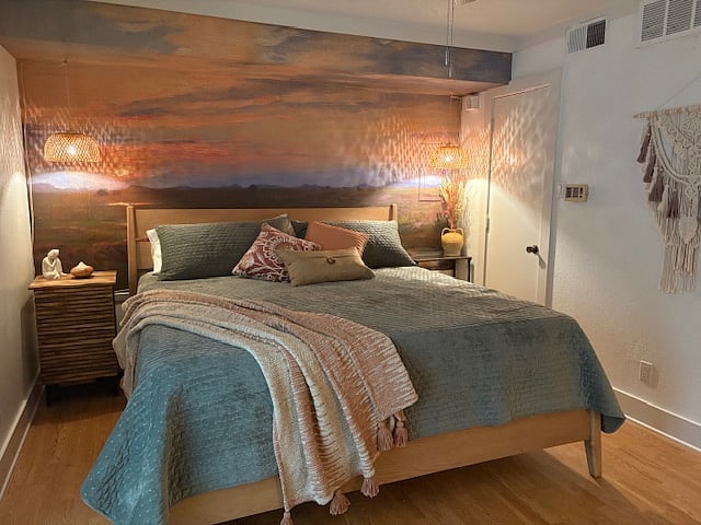 King sized bed , and sunset mural with soothing dimmable pendent lighting