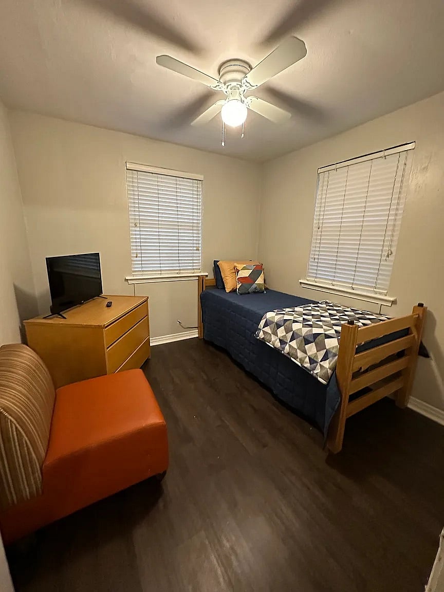 A private and cozy third bedroom featuring its own Smart TV and a spacious personal dresser. A perfect quiet corner for guests who want to unwind with their favorite shows after a long shift.