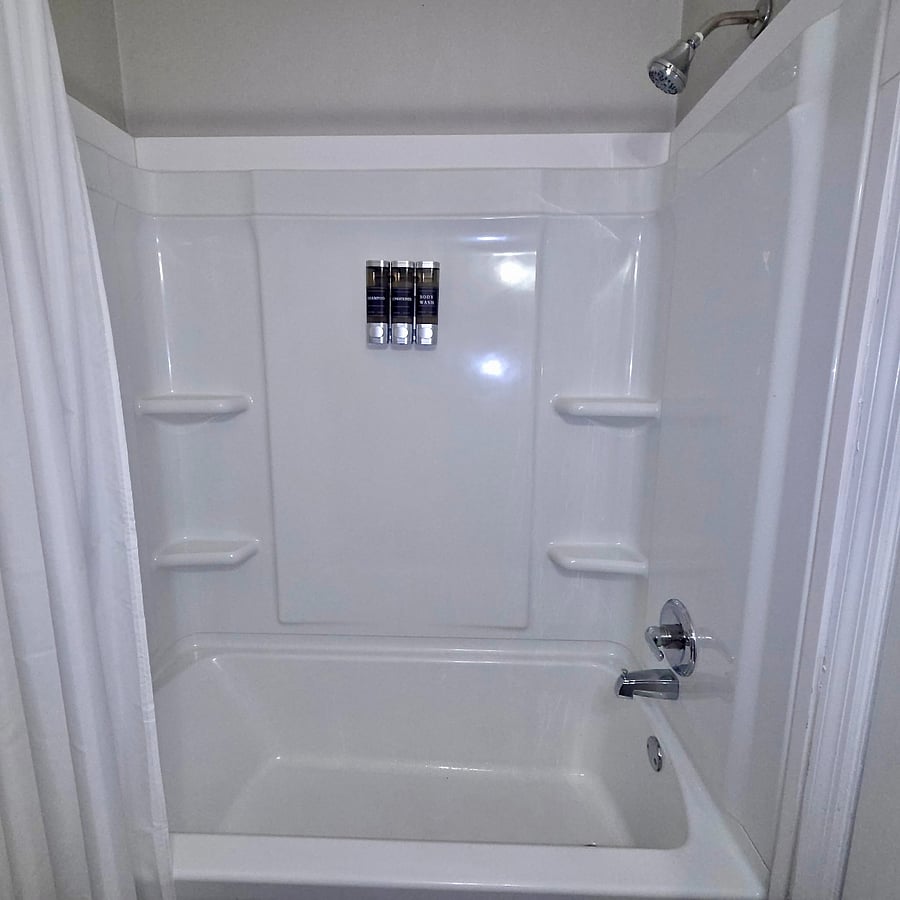 parkling clean full bathroom featuring mounted hotel-quality shampoo, conditioner, and body wash dispensers to help you pack lighter. Fresh towels and a clean, modern aesthetic provide a refreshing start to your day.