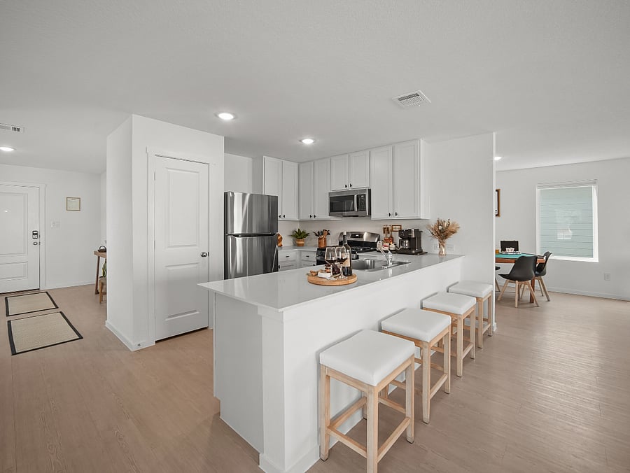 The breakfast bar and kitchen anchor the heart of the home- a welcoming space where morning coffee, shared meals, and easy conversation naturally come together.