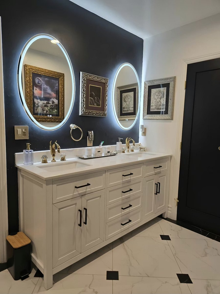Hollywood Regency style bathroom with double vanity, illuminated mirrors, and ample storage. 