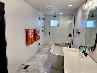 Large bathroom off of master bedroom with soaking tub, double sinks, and shower with multiple shower heads
