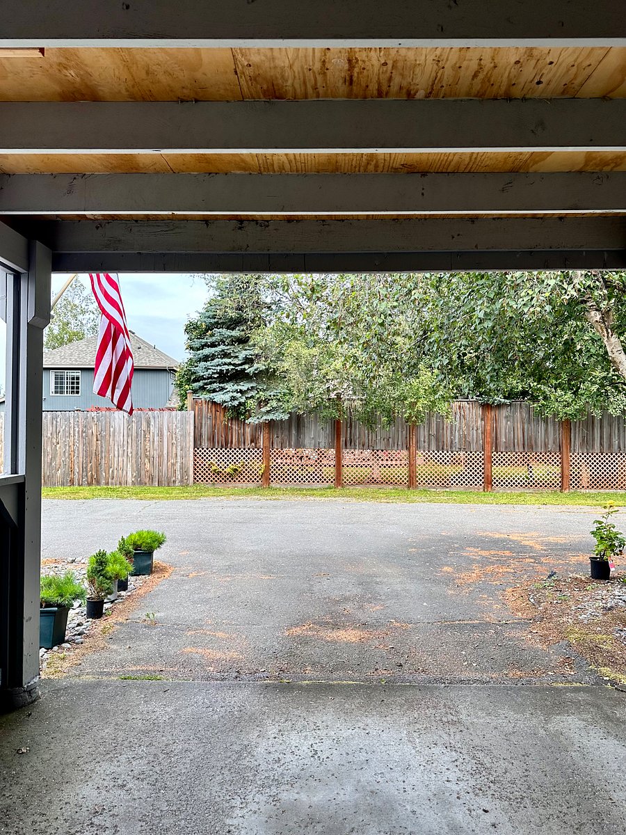 Summertime view of carport and "back fence" behind unit where a second car can be parked.