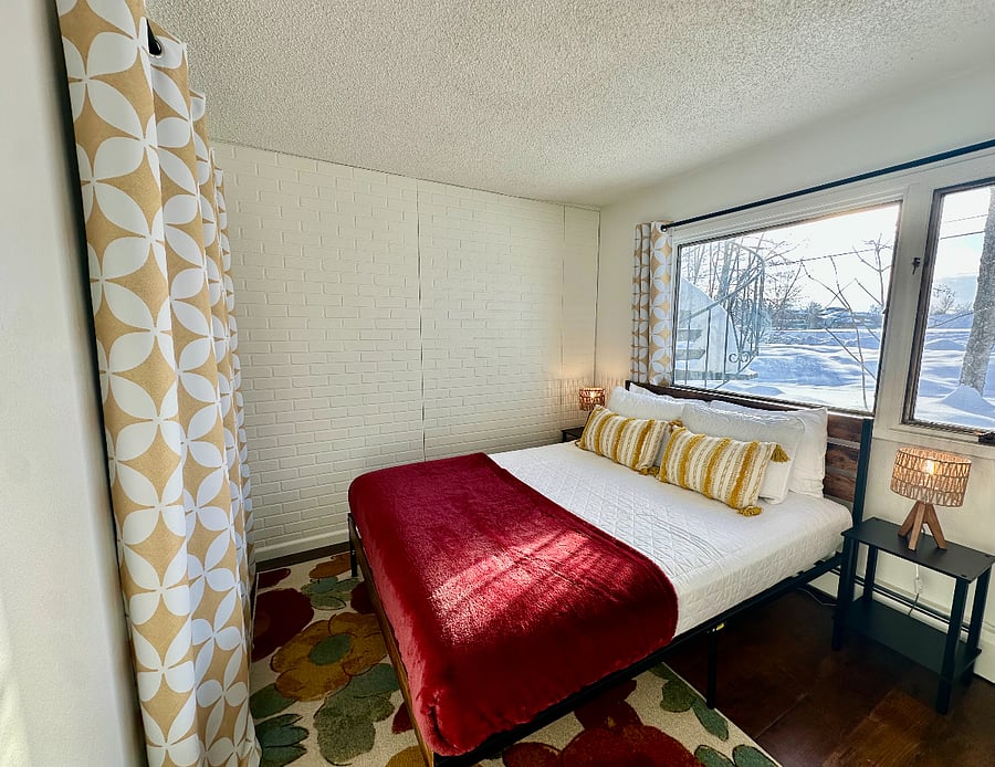 Third bedroom (ground-level, adjacent to King bedroom) with Queen bed, crisp quilted bedding, soft cotton sheets, cozy blanket, blackout curtains, and plenty (four) of pillows for a great sleep!