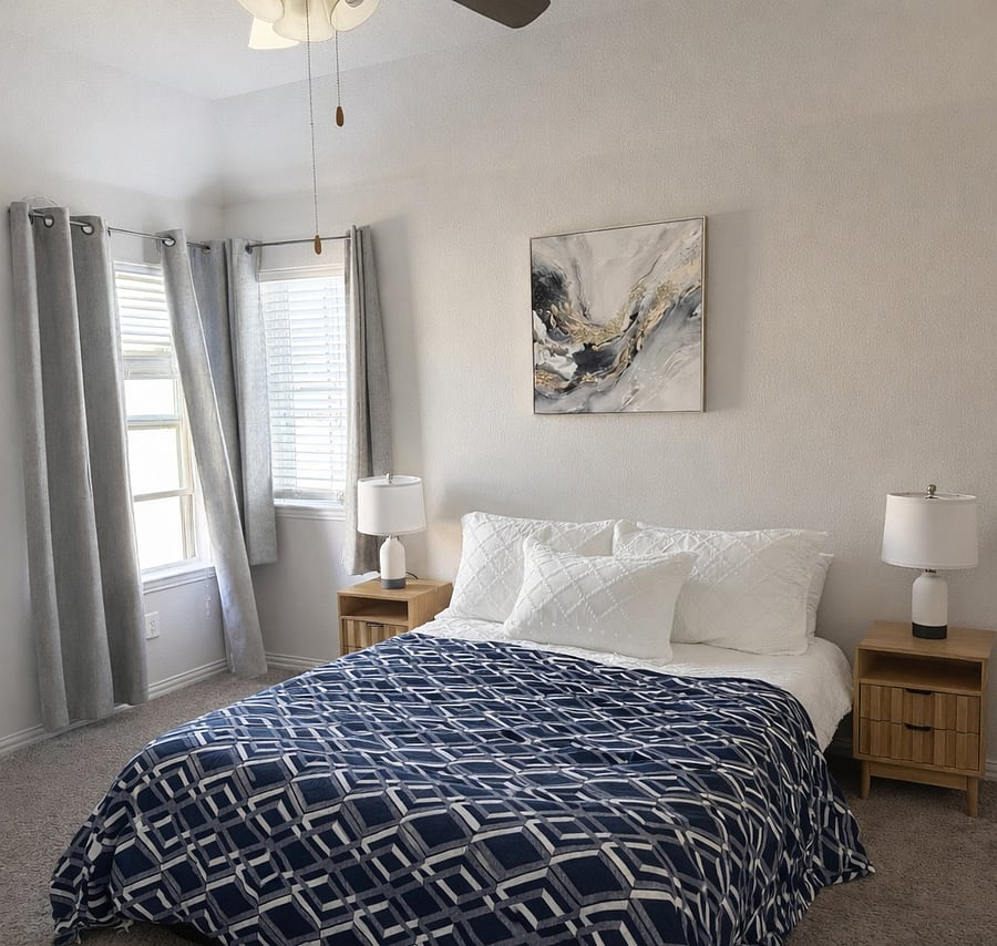 Sunny bedroom angle showing space and windows.