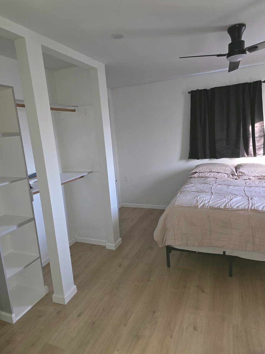 2nd bedroom suite featuring full size bed, private bathroom shower/tub combo, 60" TV, closet space shelves, remote ceiling fan.