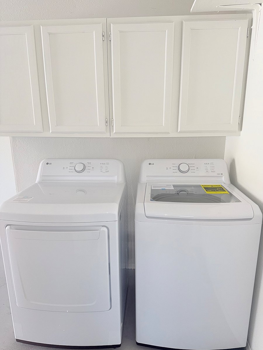 Great laundry place with new side by side washer and dryer with over head cabinets stocked with supplies
