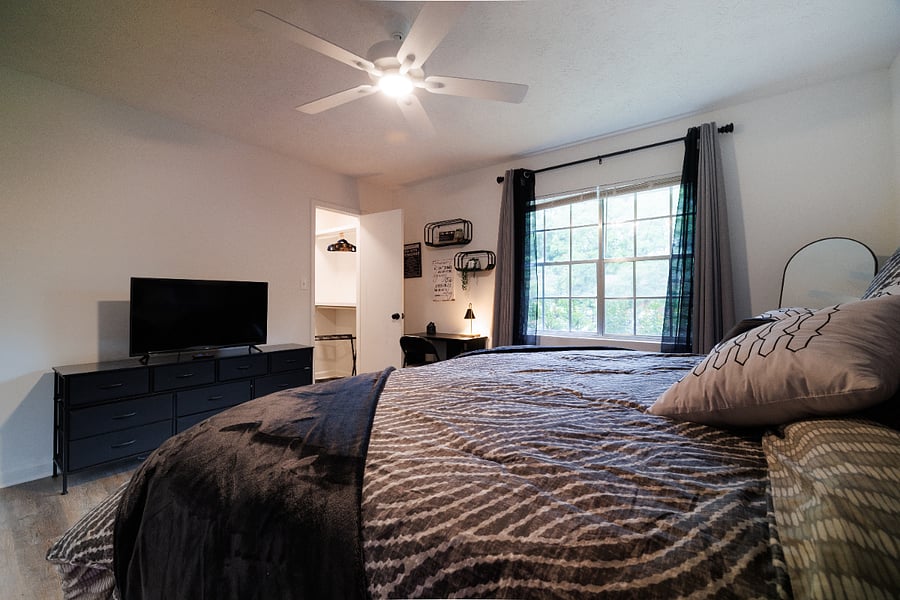 bedroom 1 set up as king, view shows room darkening curtains, smart tv, dresser, luggage rack and desk