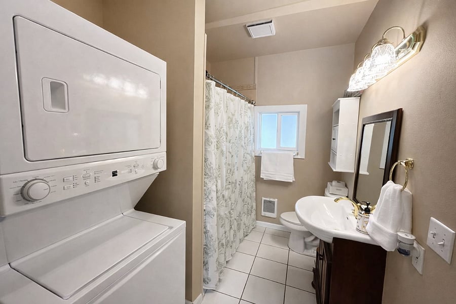 Full bathroom with soaking tub, private in-unit washer and dryer, and a window for fresh air and sunlight.