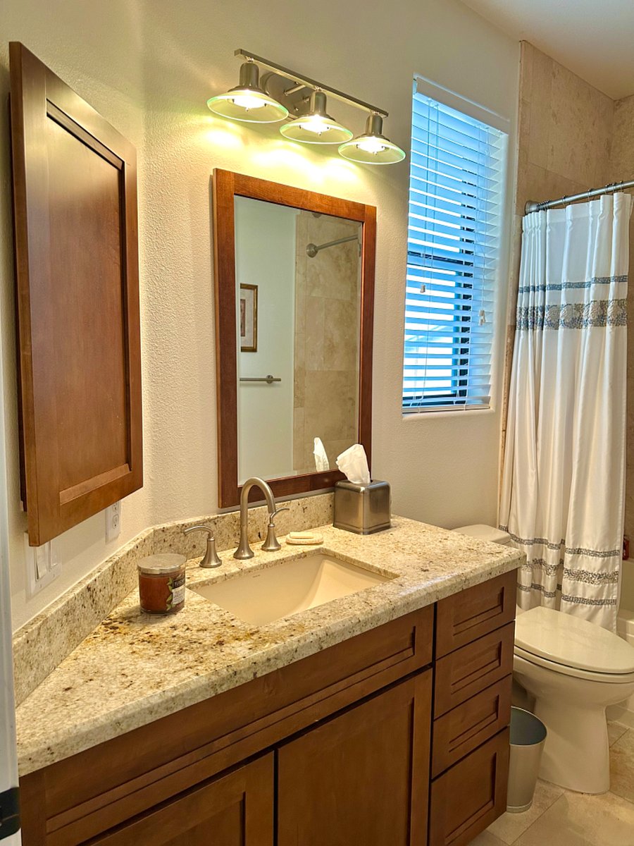 Fully stocked cupboards underneath sink, with towels, a hair dryer, cleaning supplies, etc.