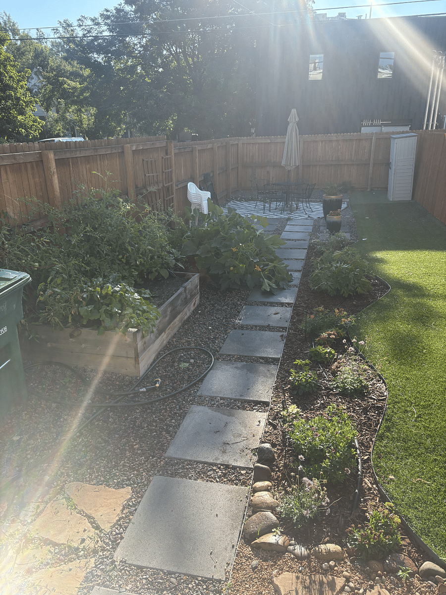 View of the backyard from the back door. There is a table with an umbrella to sit and relax. Also available is an outdoor propane grill.