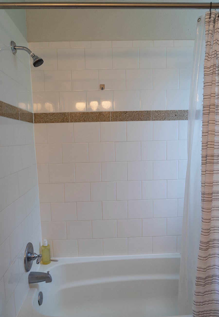 The bathroom has a window and a shower with a tub.