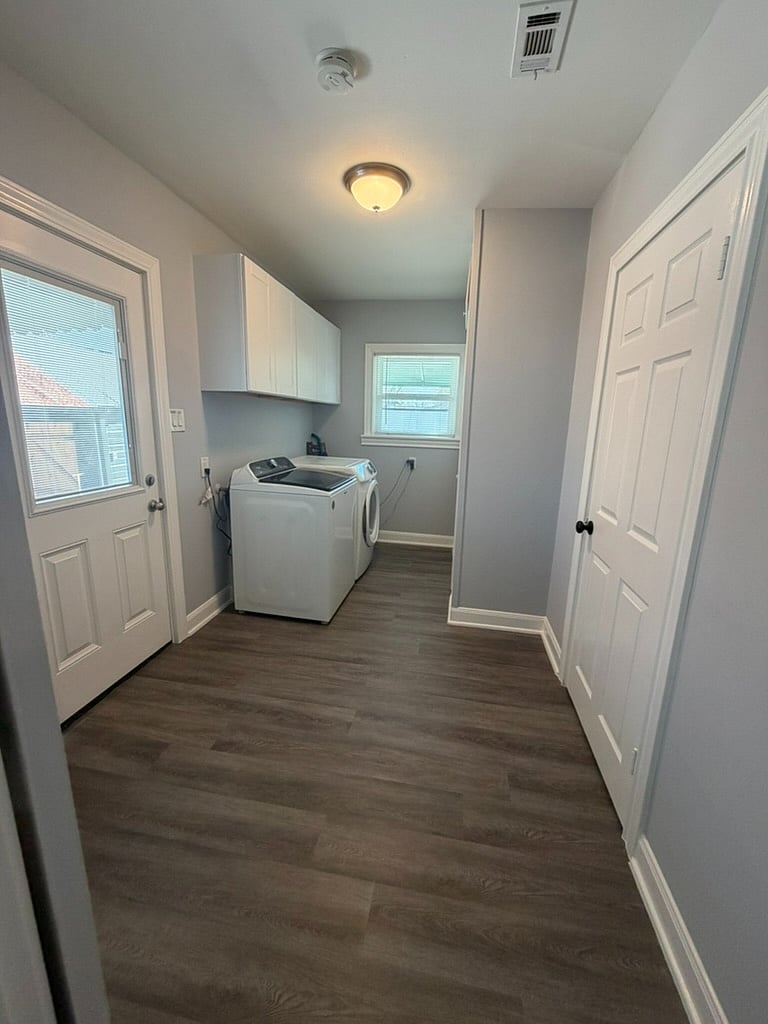 Laundry room with tankless water heater located between master bedroom and 2nd bedroom. Side entrance to house   located in room.