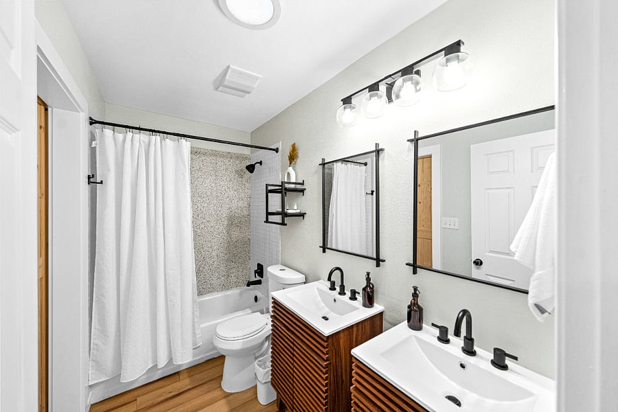 Bathroom wide angle shot of the double sinks, shower/tub and toilet.