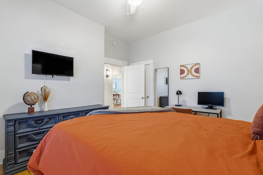 Well-designed layout with full workspace setup, smart TV, dresser storage, full length mirror and walk-in closet