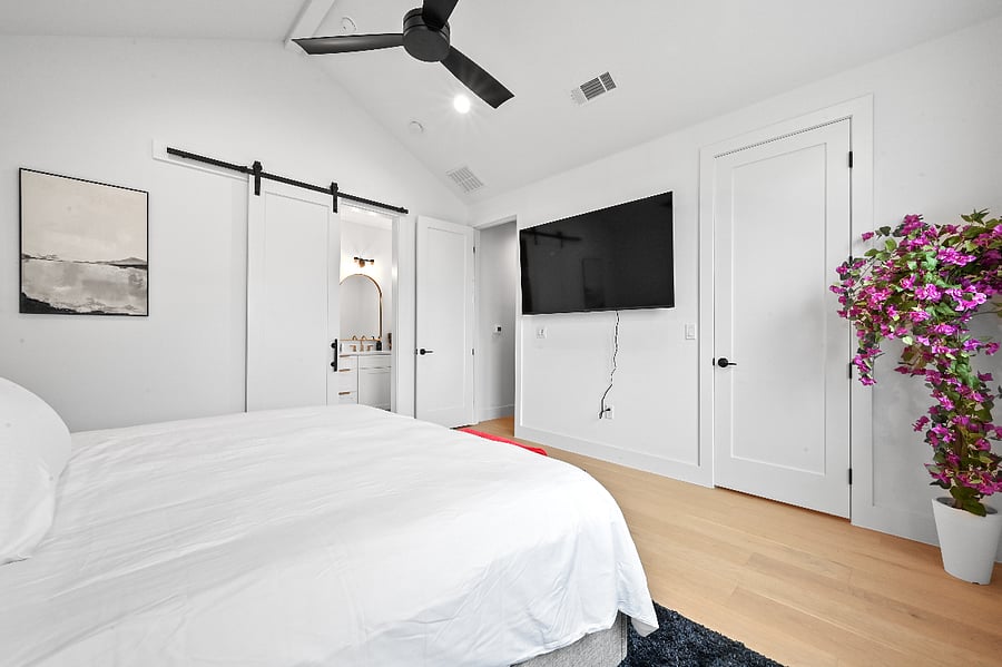 King size bed 70" TV Extra bedding Vaulted Ceilings Blackout blinds with frosted windows Extra bedding USB and USB-C Outlets Barn door to restroom Full size mirror Bedroom bench Warm lighting Bougainvillea plant