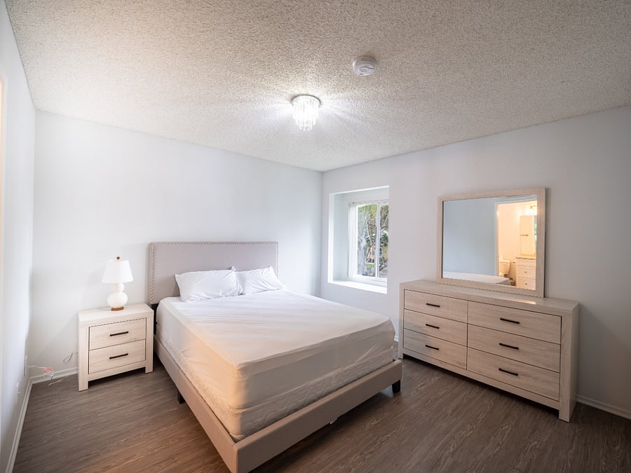 Bedroom 1 with queen size bed, dresser and mirror, night stand and lamp, bathroom