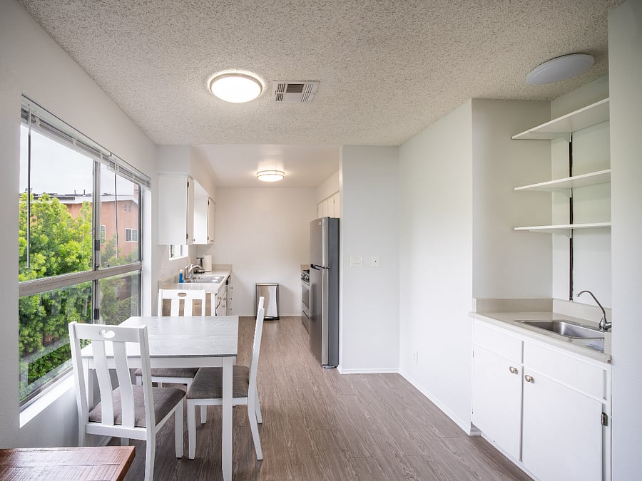 Dining room with kitchen table and chairs, kitchen, garbage pail, and wet bar. View from front door.