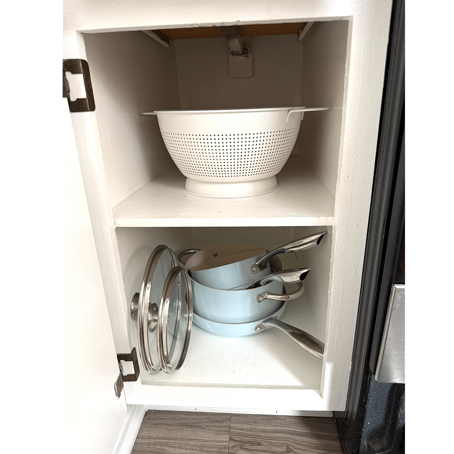 Calendar, pots and pan with lids in lower kitchen cabinet.