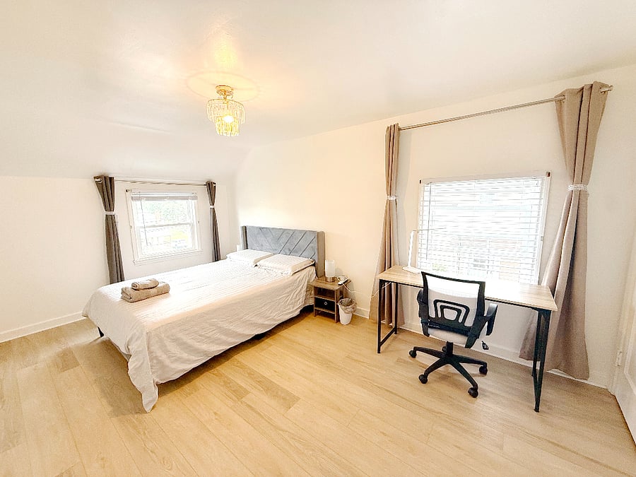 The primary bedroom includes a queen-size bed with a high-quality memory foam mattress, a computer desk and an office chair, and a built-in wardrobe