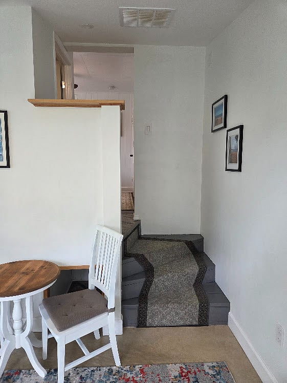stairs and privacy half-wall leading from the living area to bedroom and bathroom.