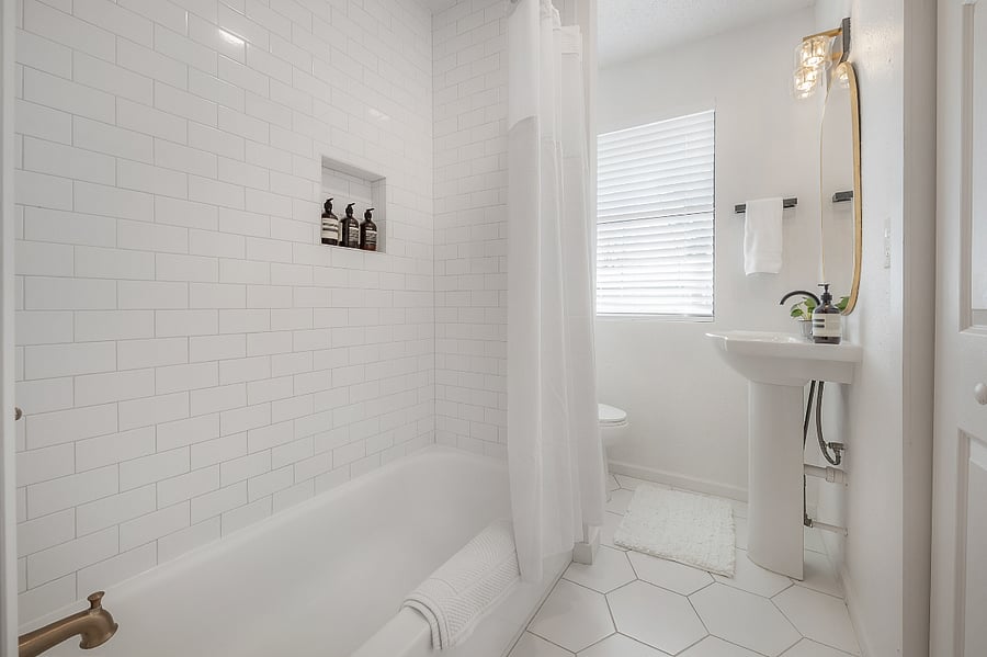 Fully renovated bathroom with tub/shower, pedestal sink, and fully stocked linen closet