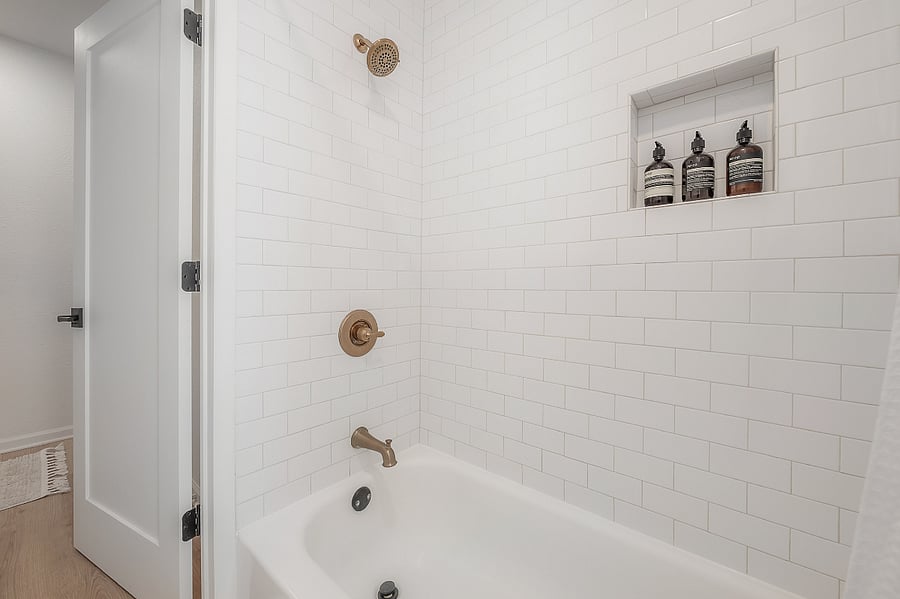 Fully renovated bathroom with tub/shower, pedestal sink, and fully stocked linen closet
