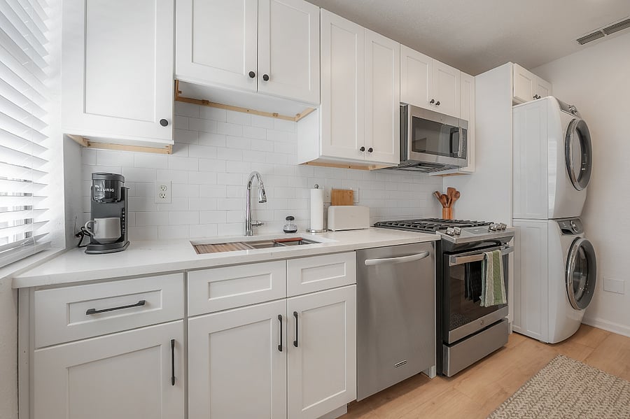 Fully renovated and stocked kitchen with gas range, microwave, dishwasher, refrigerator, and stackable washer and gas dryer