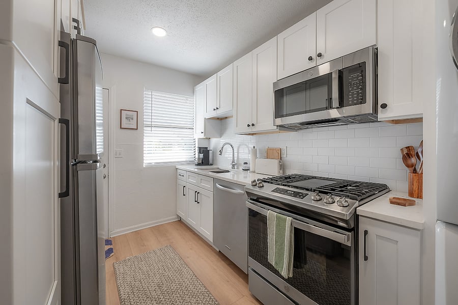 Fully renovated and stocked kitchen with gas range, microwave, dishwasher, refrigerator, and stackable washer and gas dryer