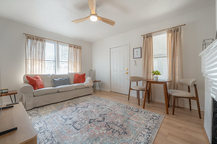 Living room with fireplace, sofa, bistro table with 2 chairs, and Smart TV.