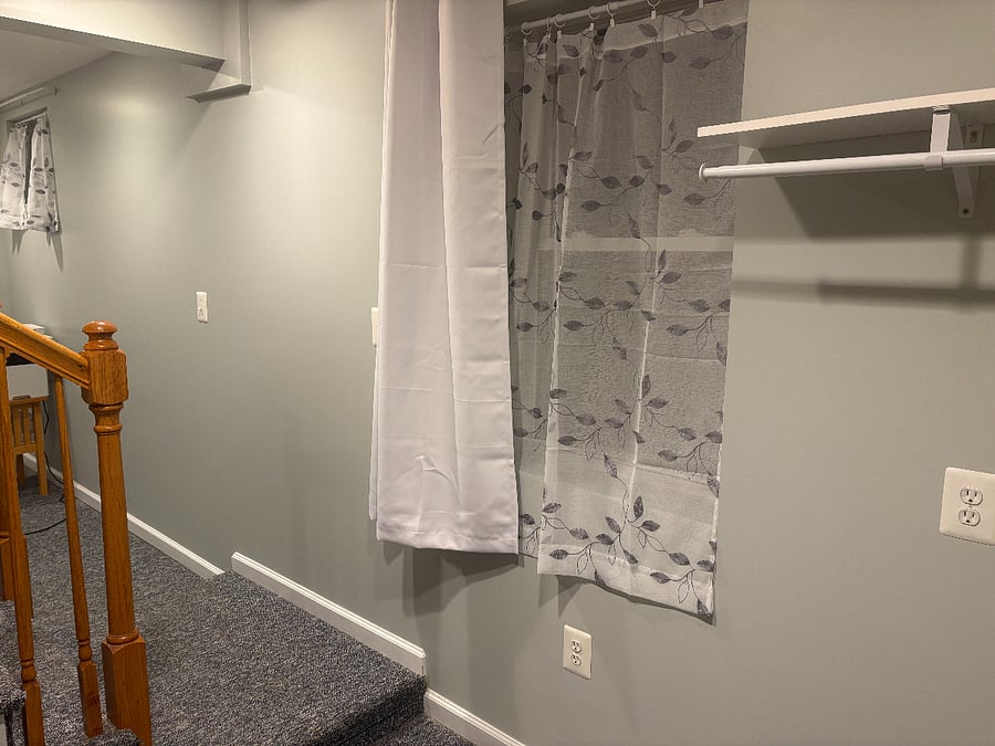 The bottom of the stairs to the basement. The laundry is to the right. There is space for hanging clothing to dry, a utility sink, washer/dryer and shelving.