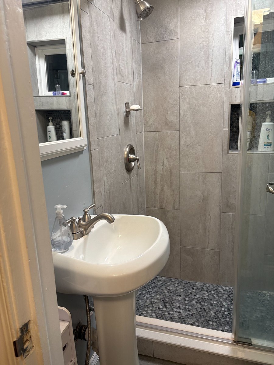 Shared bathroom sink, empty medicine cabinet and shower.