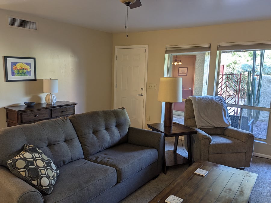 Large windows bring light into the living room and a ceiling fan keeps it comfortable.