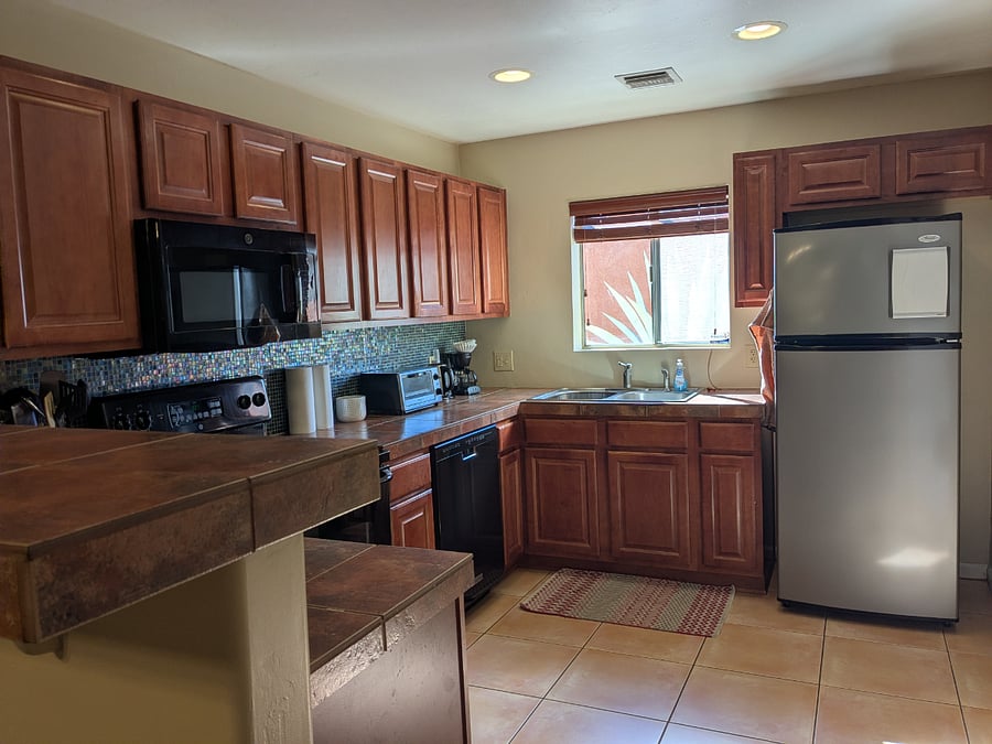 The spacious kitchen has tile countertops and backsplash. There is plenty of work space, and because the unit is on a corner it also has a sunny window over the sink.