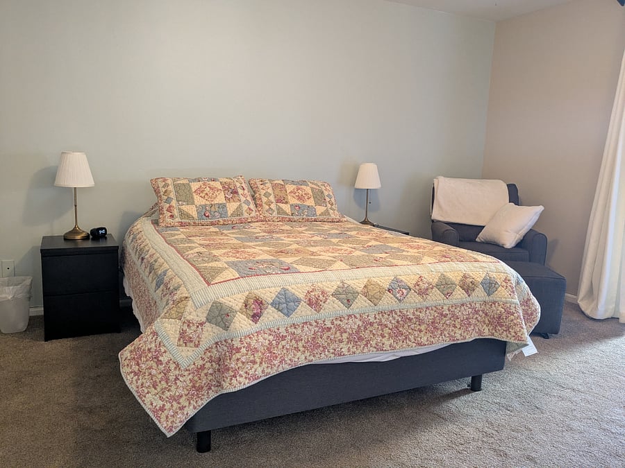Large primary bedroom has a queen bed and a comfy reading chair.