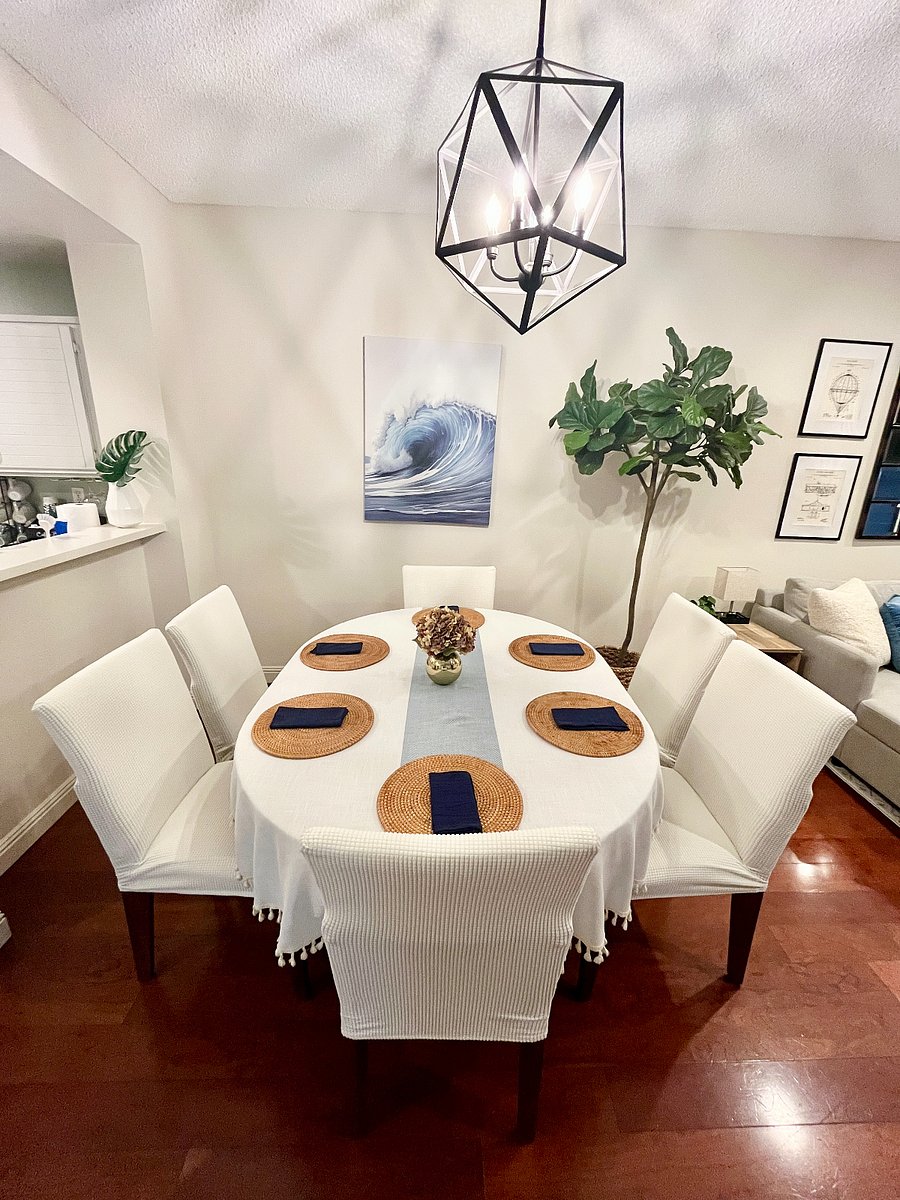 Elegant dining table for 4-6 guests with slipcovered chairs, overlooking the 65" Smart TV and connecting directly to the outdoor living and dining patio.