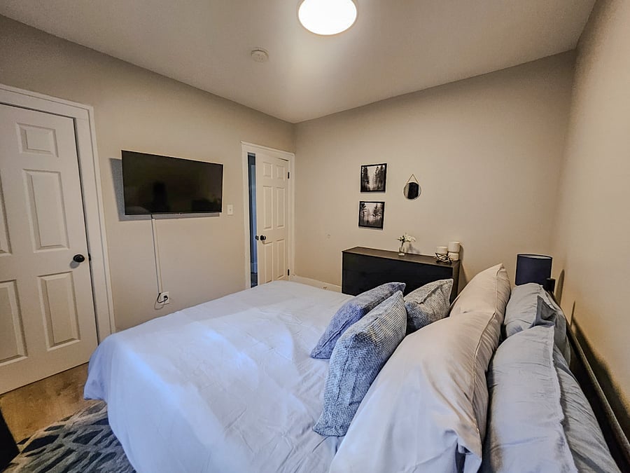 Second bedroom with 43" smart TV, storage, and nightstands with charging stations.
